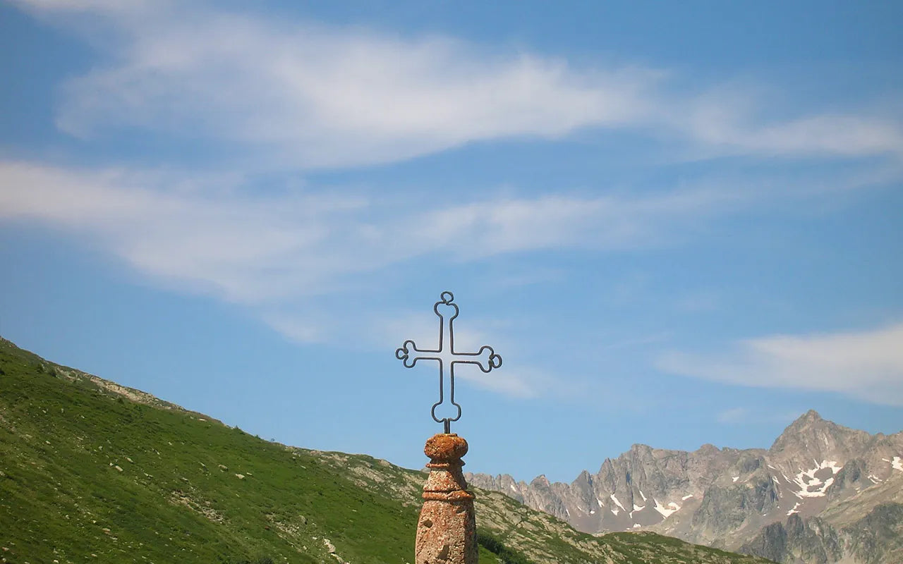 The iron cross on the Col de la Croix de Fer with mountains behind