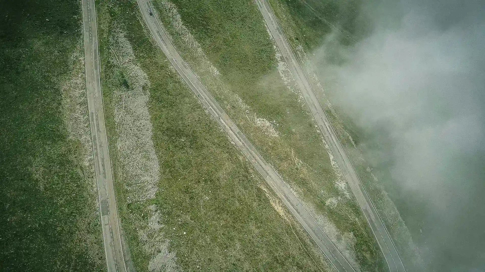 Aerial view of a mountain road switching back through the clouds