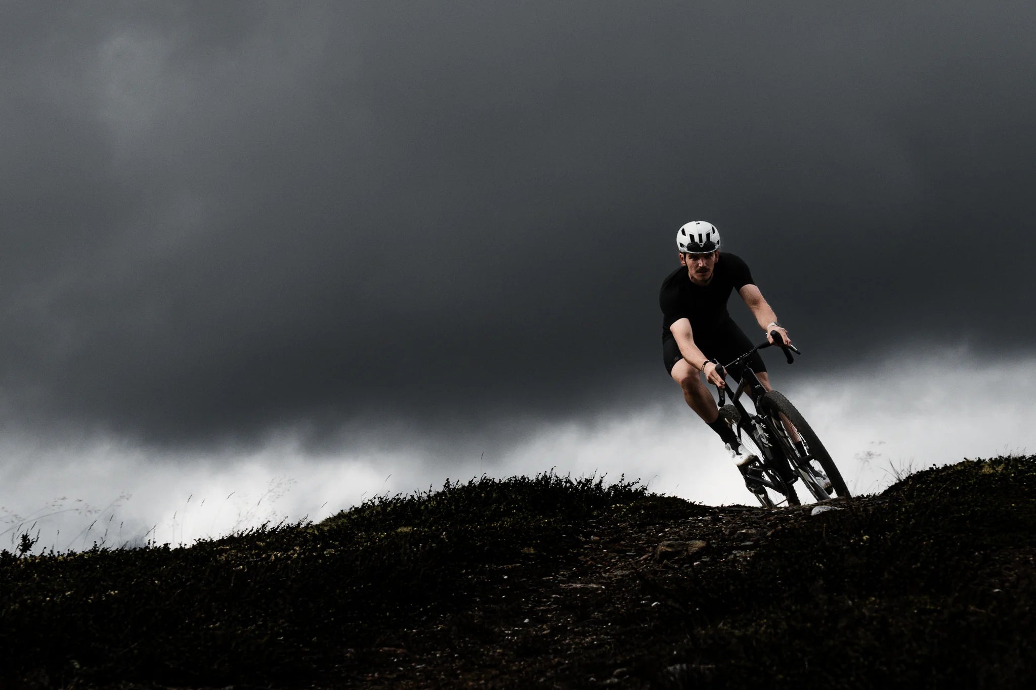 

Ciclista coronando una loma con una Fara Gr4 bajo un cielo de tormenta en Grimsdalen, Noruega