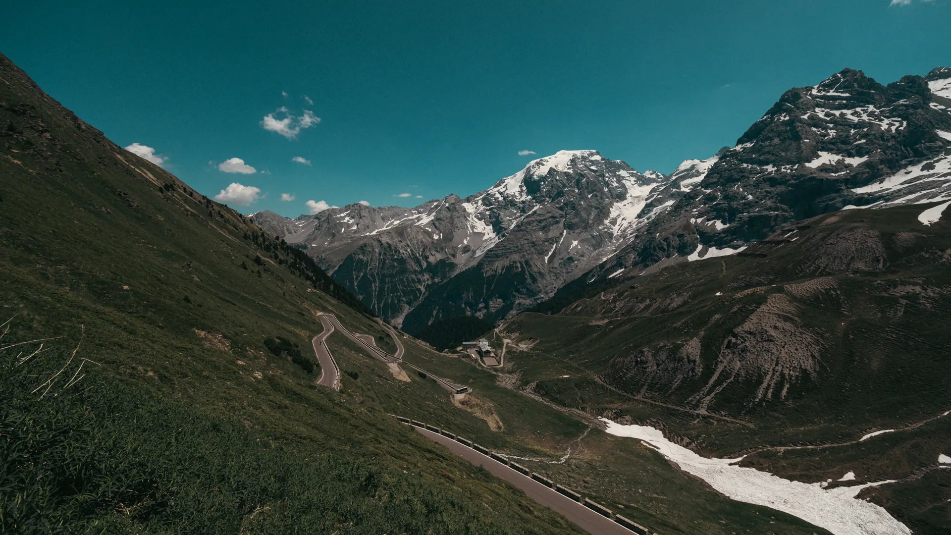 Una àmplia vall verda sota els cims nevats que envolten l'Stelvio