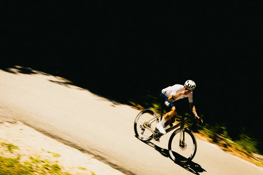 A rider sweeping along a sunlit mountain road